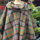 The Laird Hooded Scarf Cape in a cozy setting, emphasizing its stylish design that's perfect for festive gatherings and casual outings.